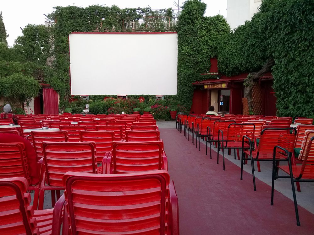 Caption: Photo of red chairs and movie screen at Thision Open Air Cinema in Athens, Greece. (Local Guide Pavlos Giovanis)