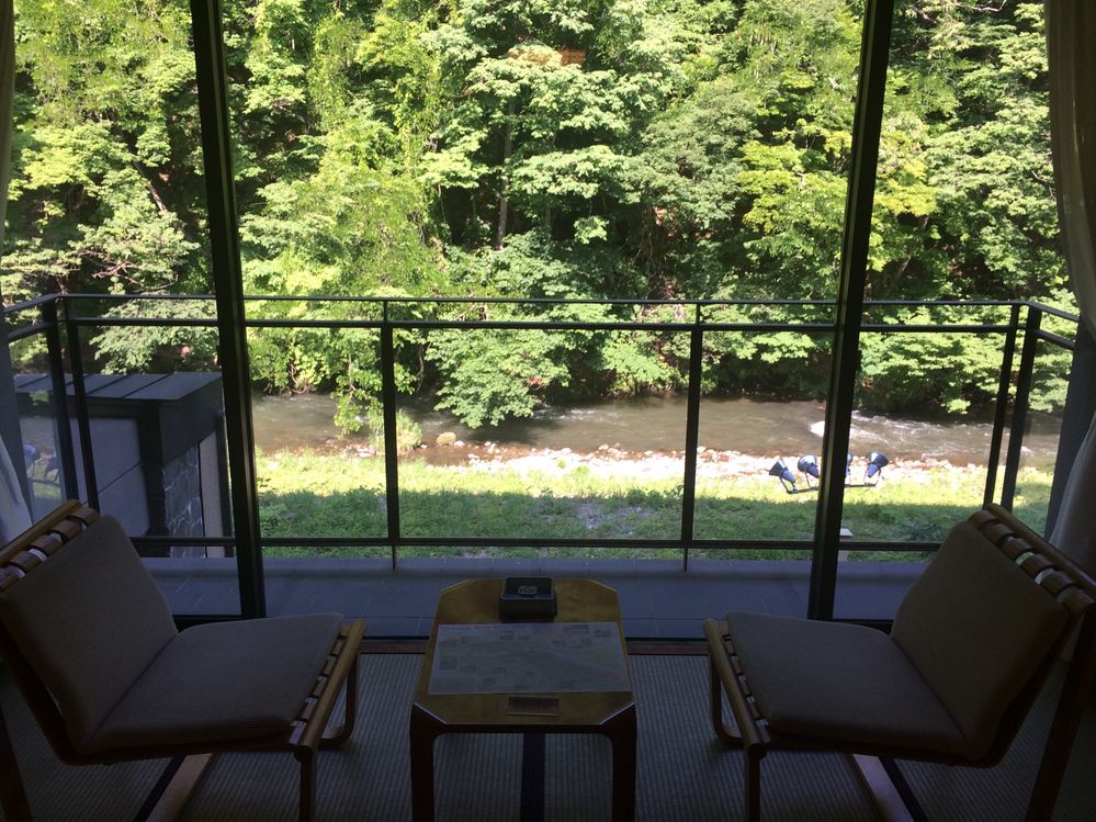 An indoor sitting area by a big windows overlooking the river.