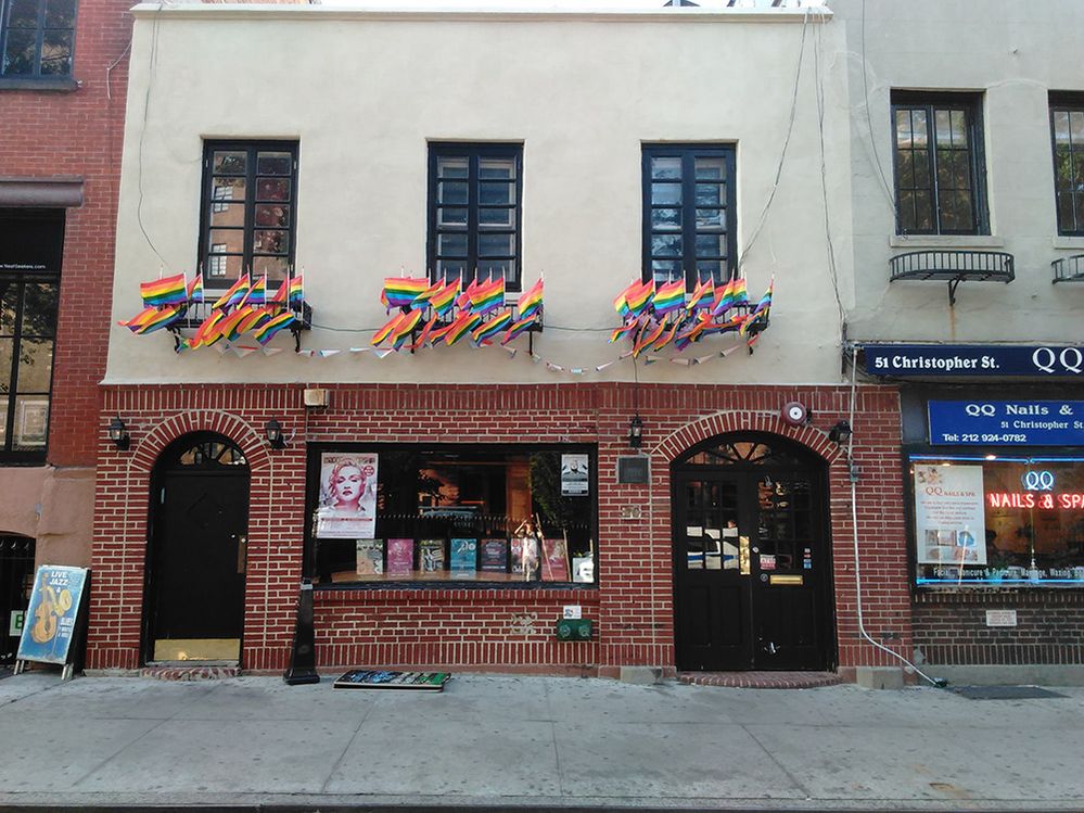 Caption: A photo of the exterior of Stonewall Inn with many rainbow flags hanging above it. (Local Guide Thomas Lau)
