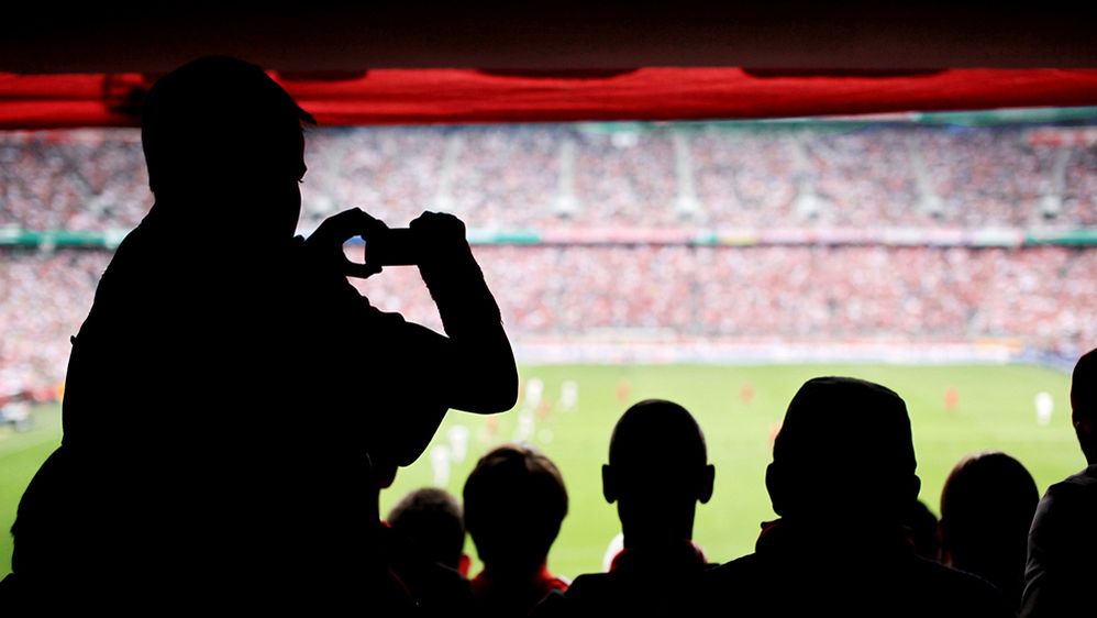 Caption: A photo of spectators taking pictures at soccer stadium. (Getty Images)