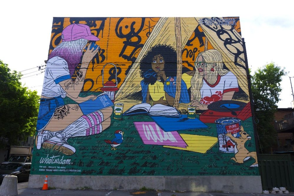Caption: A photo of a vibrant mural created by Canadian-based artist WhatIsAdam that shows three women camping together. (Courtesy of MURAL Festival)