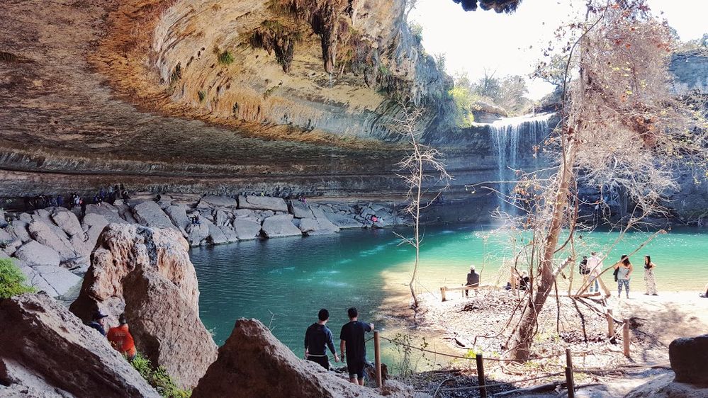 Caption: A photo of a natural swimming pool made up of a 50-foot waterfall that feeds into a canyon surrounded by a grotto in Travis County, Texas. (Local Guide Zion ghimiray)
