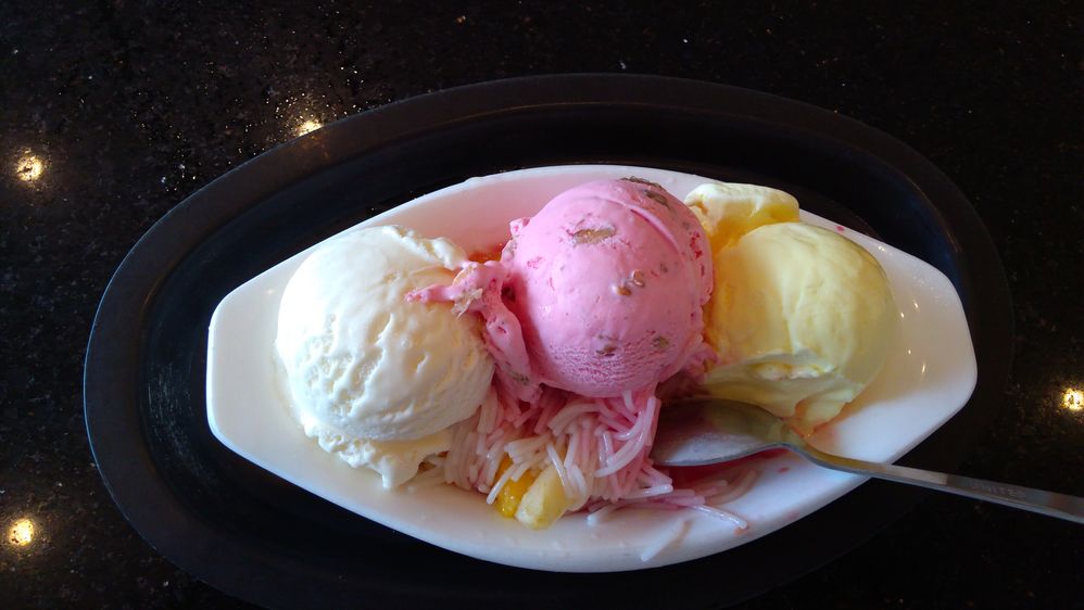 Caption: A photo of a three-scoop ice cream sundae with white, pink, and cream colored ice cream in a dish on a table at PABBA’s in Mangalore, India. (Local Guide ABHISHEK SM)