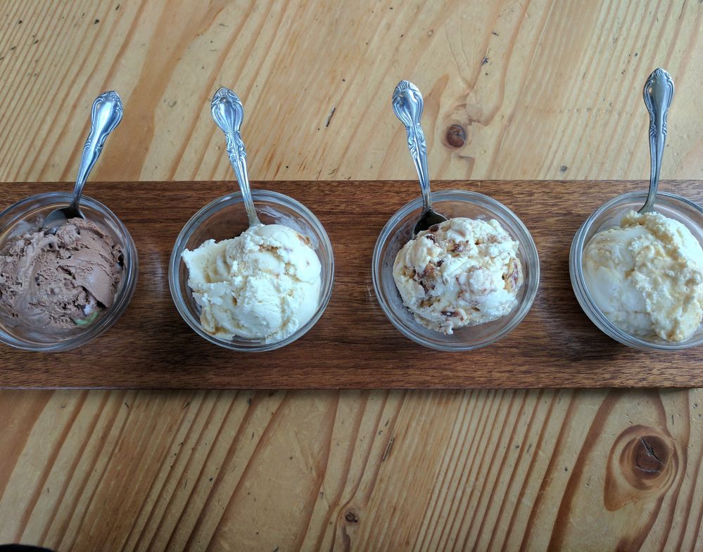 Caption: A photo of an ice cream flight at Portland, Oregon’s Salt & Straw featuring four scoops of ice cream in small glass bowls with metal spoons on a wooden board. (Local Guide Louis Tran)