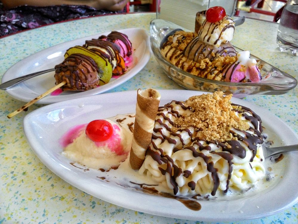 Caption: A photo of three overflowing ice cream sundaes — one traditional, one served on a platter with a rolled wafer cookie, and one served on a wooden skewer with fruit — from Zangrandi Ice Cream in Surabaya, Indonesia. (Local Guide Intan Primadewati)