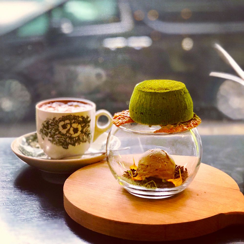 Caption: A photo of a cup of coffee and Non Entrée Dessert Cafe’s “Match Avalanche,” which consists of a matcha-flavored lava cake balanced with candy on top of a glass over a scoop of ice cream. (Local Guide James Loo)