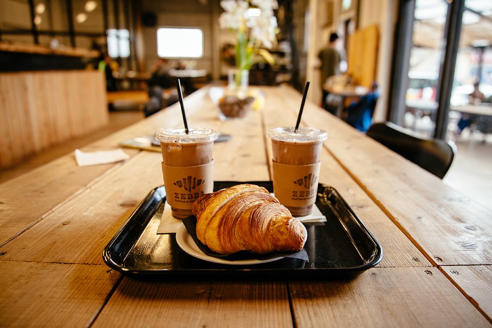 Caption: A photo of iced coffees and croissant on a tray on a table at Zebra Coffee & Croissant in Tokyo, Japan. (Local Guide K)