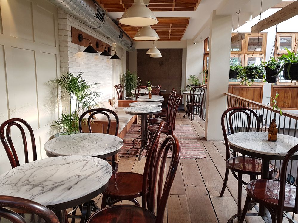 Caption: A photo of empty tables and chairs at Lucky Cat Coffee and Kitchen in Jakarta, Indonesia. (Local Guide Imam Arief)