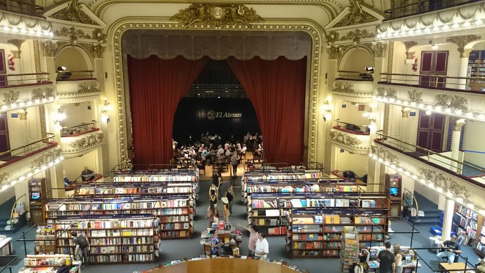Caption: A photo of El Ateneo Grand Splendid, a multi-tiered bookstore housed in a converted theater with rows of bookshelves where the orchestra used to be and a cafe on the former stage. (Local Guide Luis Salinas)