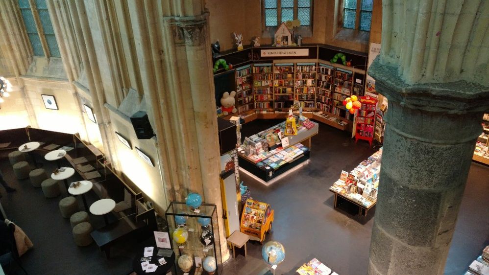 Caption: A photo of Boekhandel Dominicanen, a bookstore Maastricht, Netherlands housed in a stunning former church,  showing the children’s books area as well as the store’s cafe among stone pillars. (Local Guide Martijn van Wagtendonk)