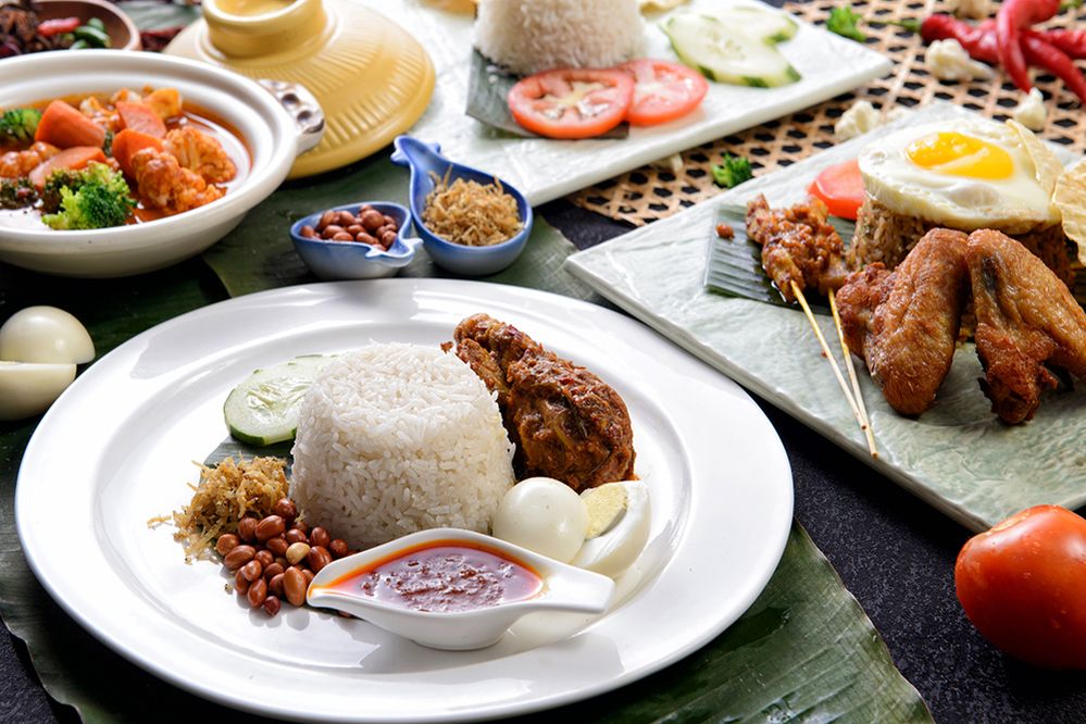 Caption: Foto makanan rendang ayam dan nasi lemak dikelilingi aneka makanan khas Indonesia. (Getty Images)