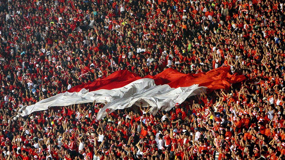 Caption: Foto kerumunan ramai-ramai mengibarkan bendera Indonesia (Getty Images)