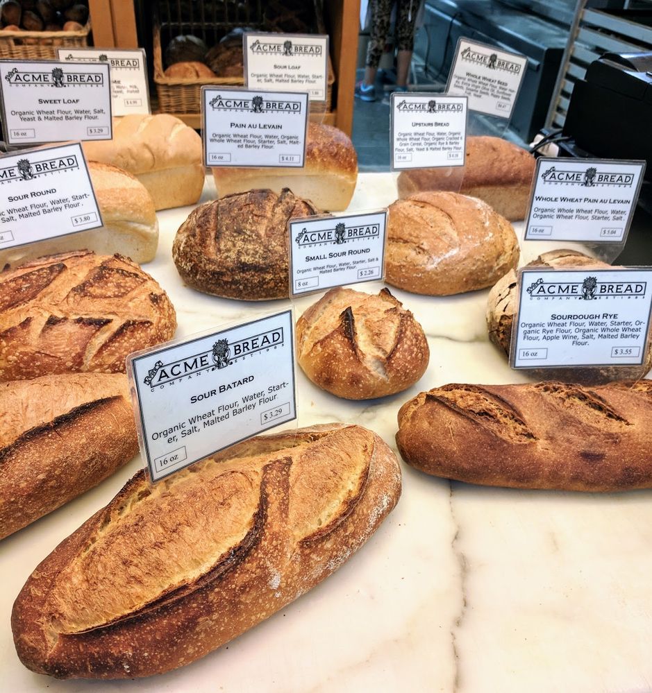 Caption: A photo of variety of loaves of bread in different sizes with signs that show their name, price, ingredients, and size presented on a counter at Acme Bread Company in San Francisco, California. (Local Guide Ed Westberg)