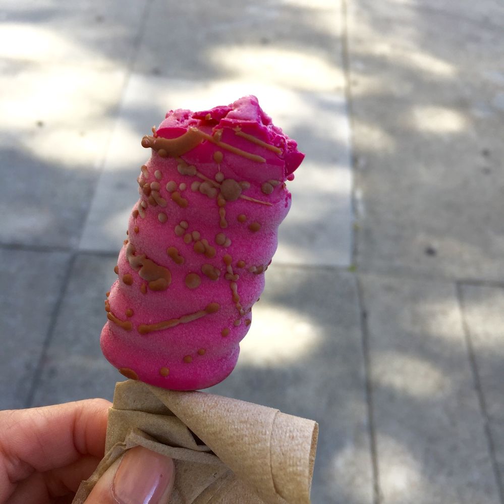 Caption: A photo of a hand holding a raspberry-flavored Gelato pop from Sixth Course after taking a bite. (Local Guide Mikyong Kim)