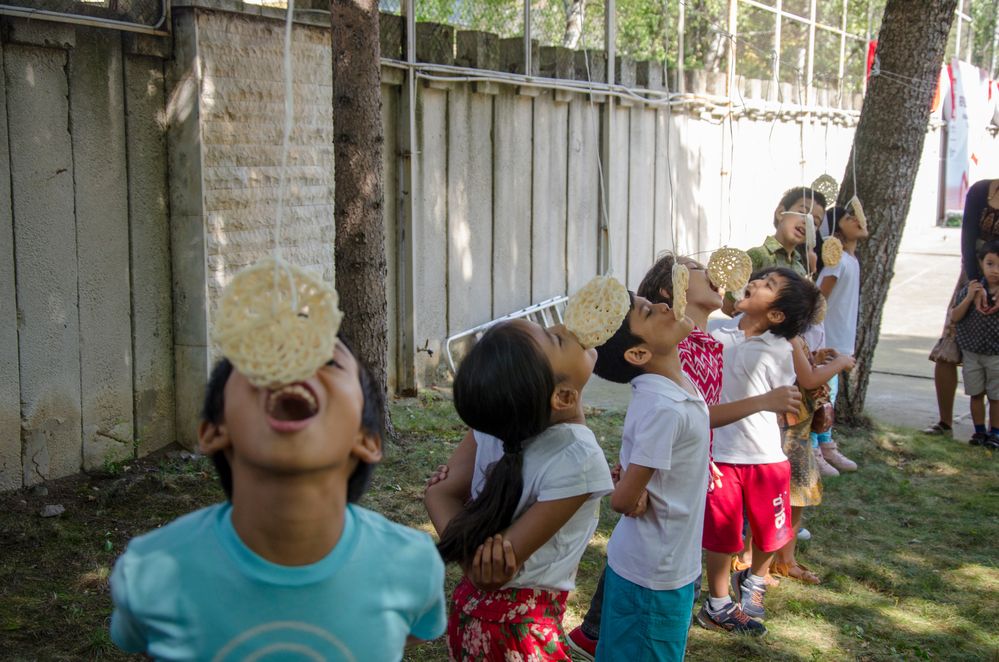 Keterangan: Foto anak-anak yang berpartisipasi dalam lomba makan kerupuk.  Kerupuk digantung pada seutas tali dan anak-anak mencoba memakannya tanpa menggunakan tangan.