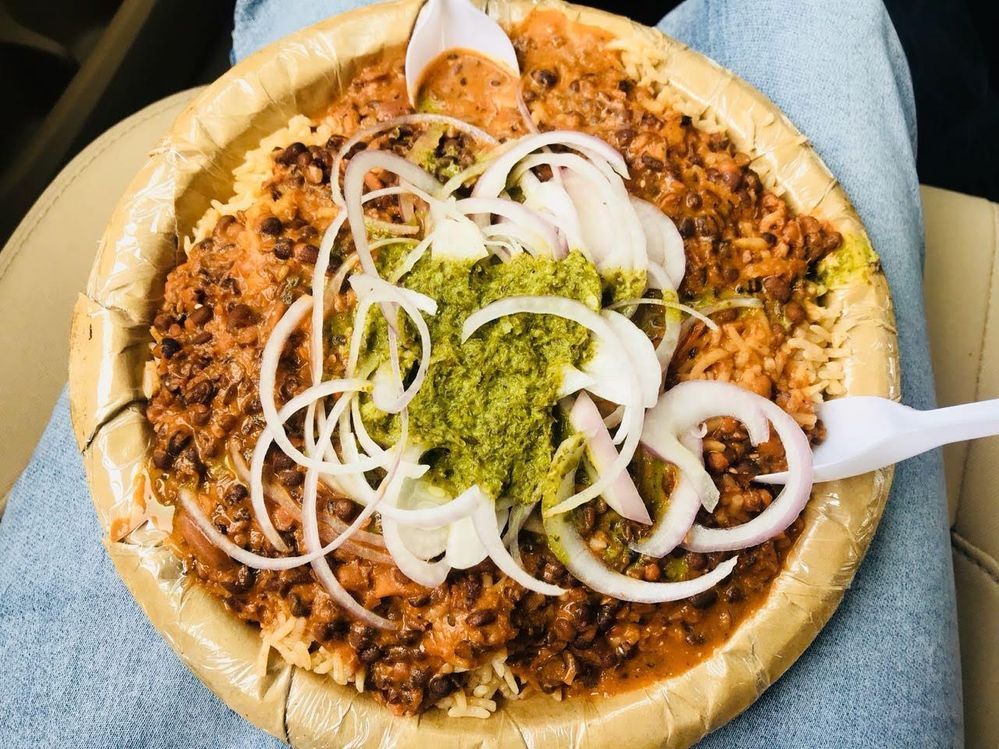 Caption: A photo of a rice dish with a green chutney and onions on a plate with two plastic spoons from Jain Chawal Wale Atulyam in Delhi, India. (Local Guide  Anurag Chaudhary)