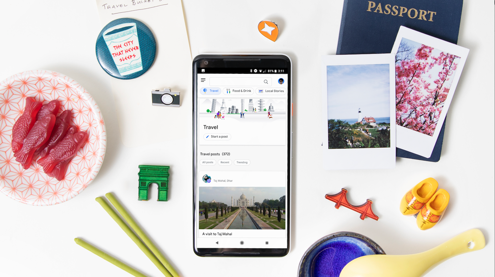 Caption: A photo of a phone displaying the Travel section on the redesigned Connect website surrounded by various pins, a passport, two polaroid photos, a plate of gummy fish, and other colorful props.