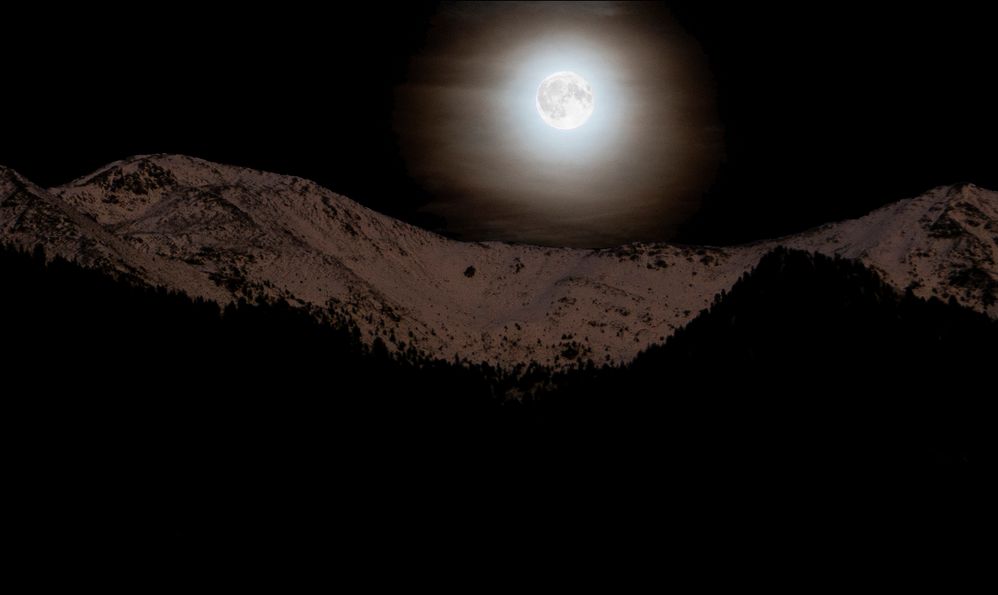 Rising moon over snowy mountains