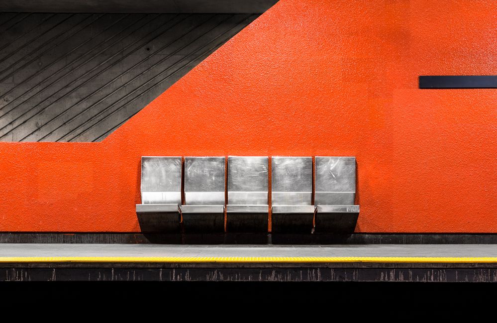 Caption: A photo of five chairs in front of an orange painted wall at Lasalle station in Montreal, Canada. (Courtesy of Chris M. Forsyth)