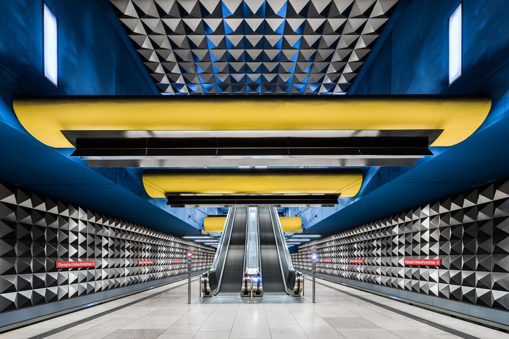 Caption: A photo of two escalators inside of the Olympia-Einkaufszentrum train station in Munich, Germany. (Courtesy of Chris M. Forsyth)