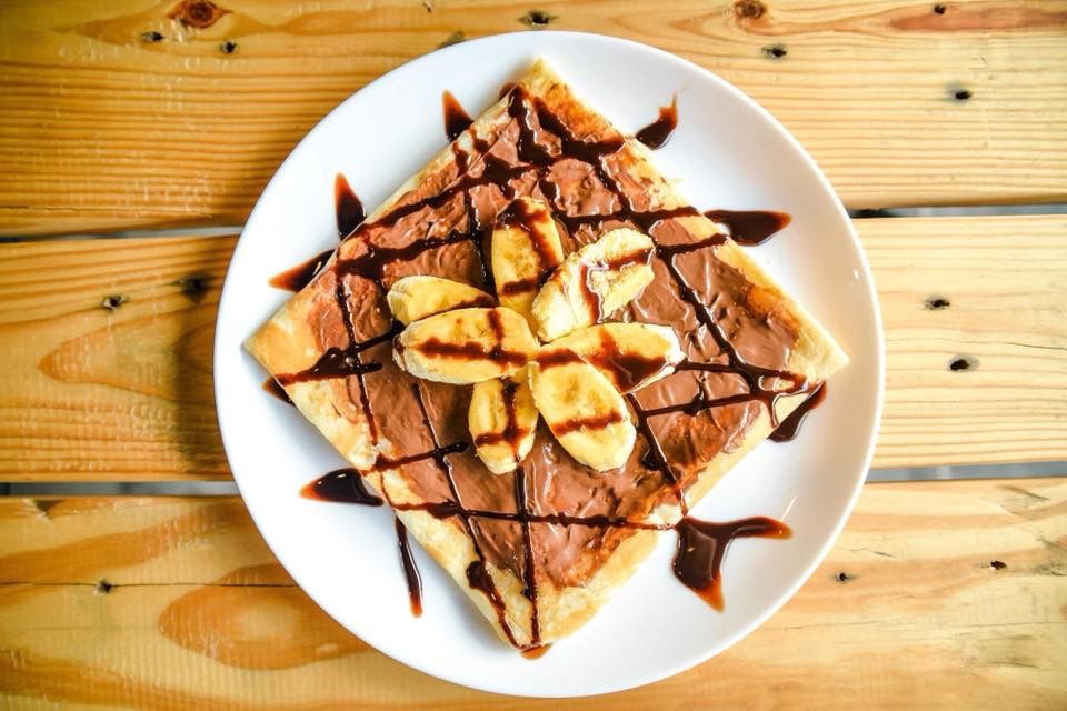 Caption: A photo of an overhead view of a dessert with banana and chocolate on a plate. (Local Guide Dids Consing)