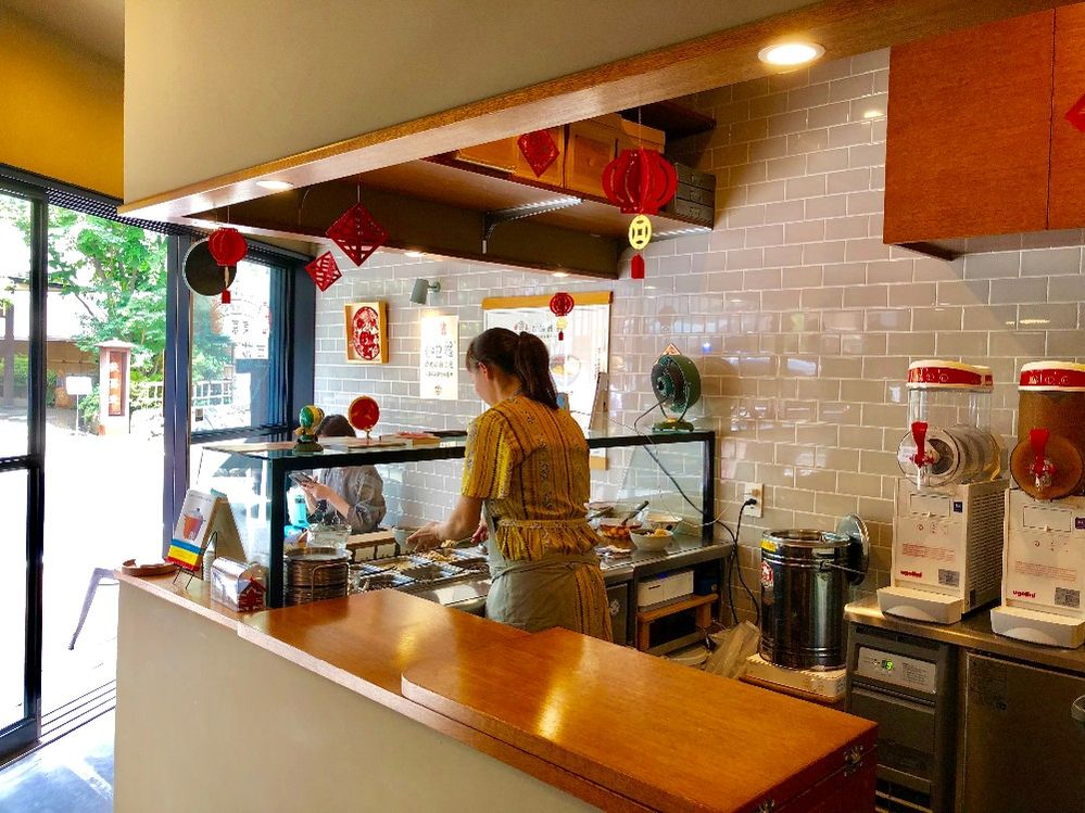 Caption: A photo of the back view of a woman filling a bowl with ingredients behind the counter at Tokyo Mamehana Kōbō, a dessert shop in Tokyo, Japan. (Local Guide 山雲海月)