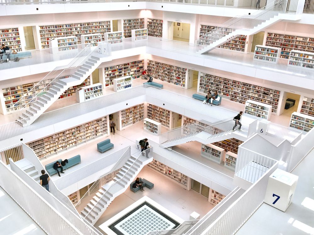 Caption: A photo of the interior of the Public Library Stuttgart Stuttgart, Germany that shows many different levels connected by white staircases. Each level has wall-to-wall bookshelves filled with books. (Local Guide Юра Козырев)