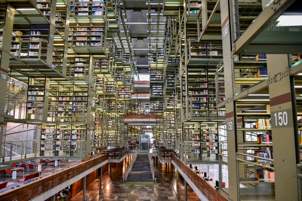 Caption: A photo of the interior of Biblioteca Vasconcelos, a library in Mexico City, Mexico, that shows a vast array of mismatched floors with transparent walls filled with bookshelves. (Local Guide David Nieto)