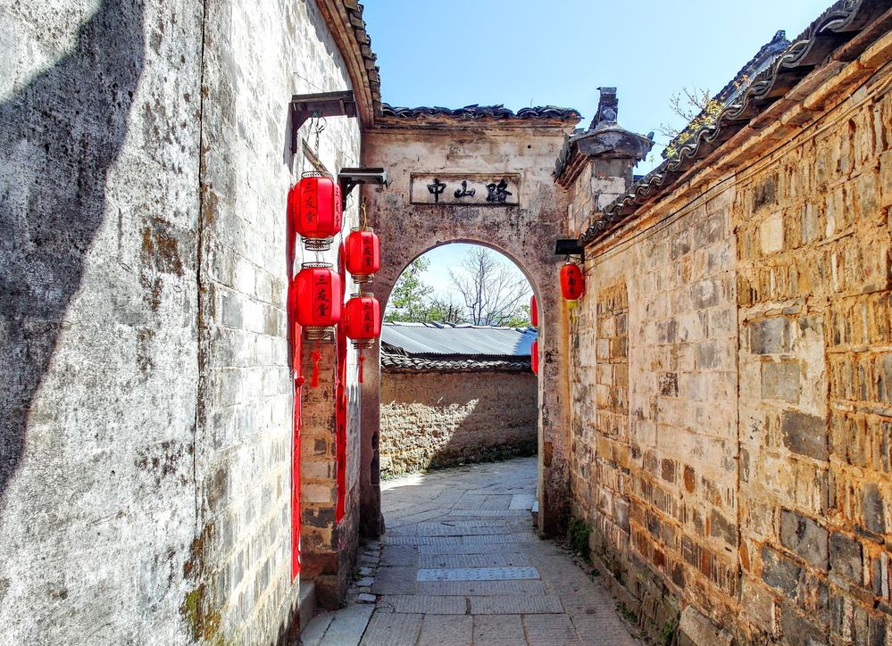 Caption: A photo of a stone alley and archway with lanterns hanging in Hongcun, Huangshan City, China. (Local Guide Сергей Серебряков)