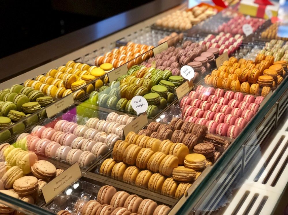 Caption: A photo of many rows of colorful macarons in different flavors in a display at Pierre Herme in Paris. (Local Guide Eddie Huynh)
