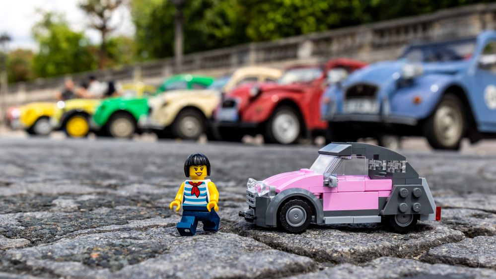 Caption: A photo of a LEGO minifigure on the street next to a pink and grey car made of LEGOs with a row of real cars in different colors visible in the background at Tuileries Garden in Paris, France. (Local Guide Julien Ballester)