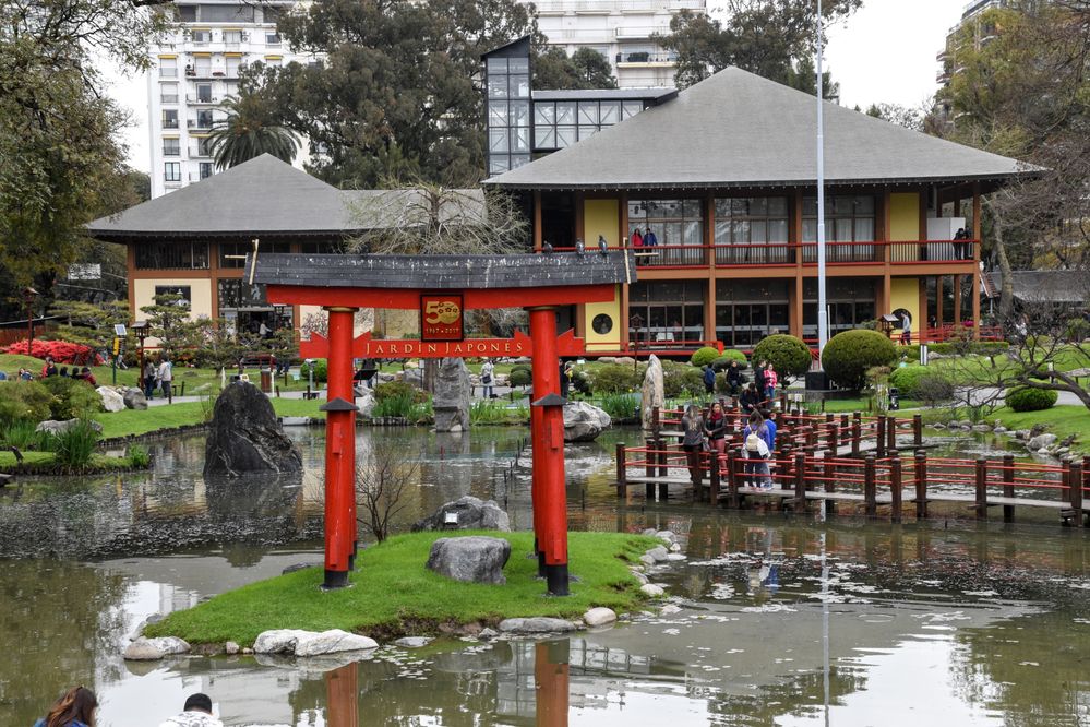 Caption: photo of the Torii that commemorates the 50 years of the garden, the zigzag bridge next to it, and the main building on the background.