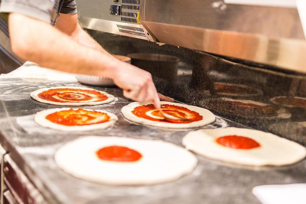 Caption: A photo of a person spreading sauce on dough at Ristorante Pizzeria Rubina in Concorezzo, Italy. (Local Guide Massimo Pastori)