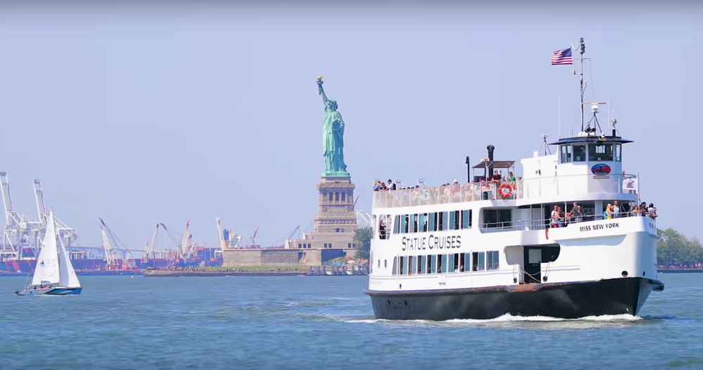 Caption: A still from the Google Local Guides YouTube video “On My List: New York” showing a white tour boat called “Miss New York” in the New York Harbor just past the Statue of Liberty.