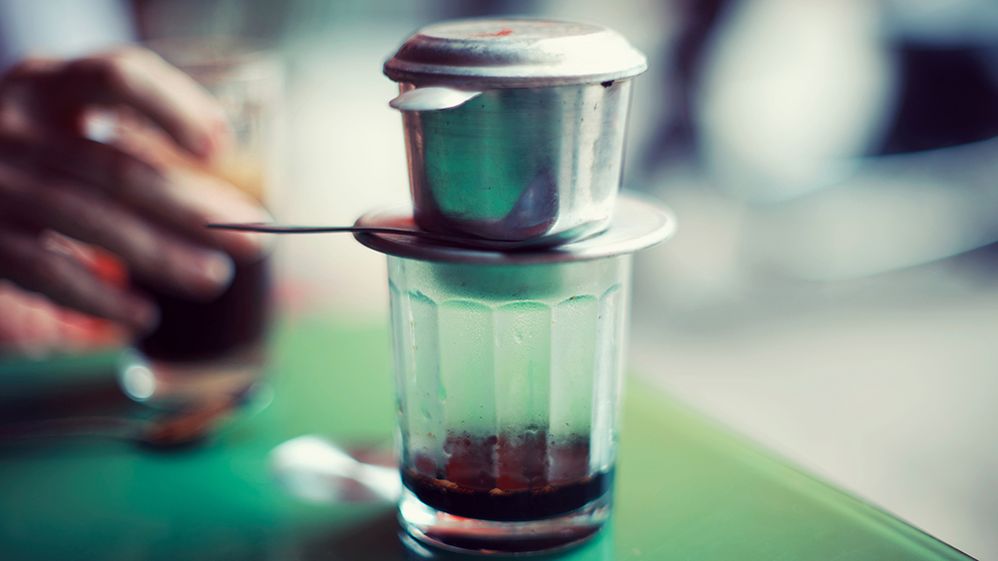 Caption: A photo of cà phê đá, a popular Vietnamese coffee drink, with a small metal drip filter above a glass with coffee at the bottom. (Getty Images)