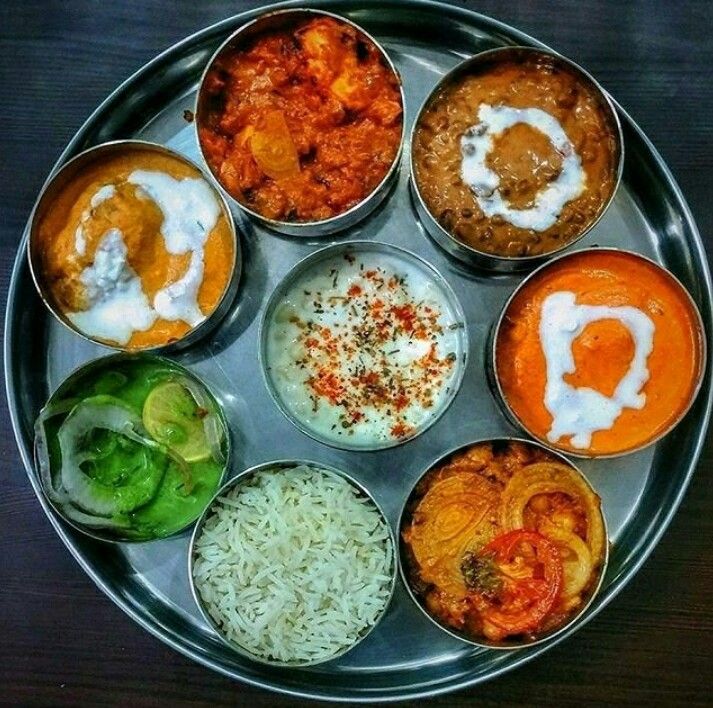 Caption: A photo of thali from Suruchi Restaurant in Delhi, consisting of eight stainless steel bowls of different types of food on a circular stainless steel platter. (Local Guide S a)