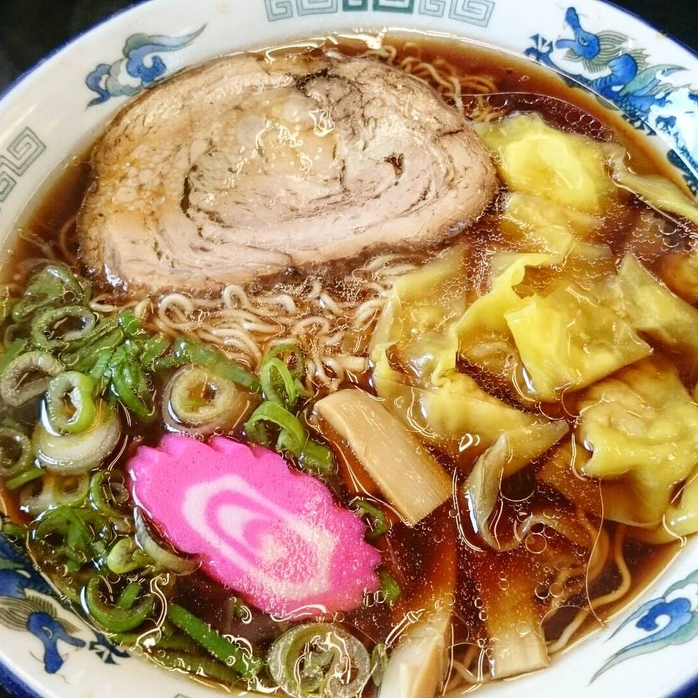 Wonton, sliced loast pork, bamboo shoots, fish cakes, and green onion are on the ramen of soy sauce flavor. The noodles are thin and wrinkled.