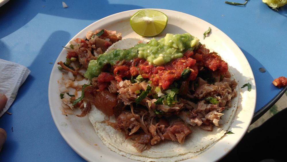 Caption: A photo of a taco topped with salsa, onions, cilantro, and green sauce on a plate with a slice of lime on a blue table at Taqueria El Abanico in Mexico City. (Local Guide paul gonzalez)