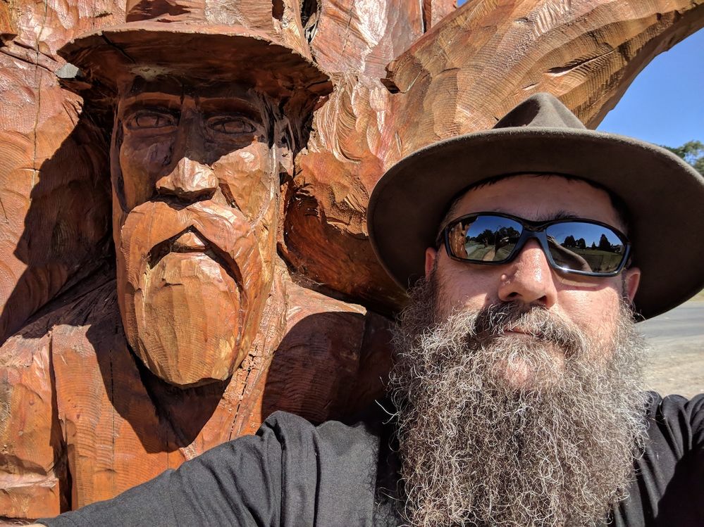 Caption: A photo of Paul wearing a hat and sunglasses next to a wood carving of a man that looks like Paul (Local Guide @PaulPavlinovich)