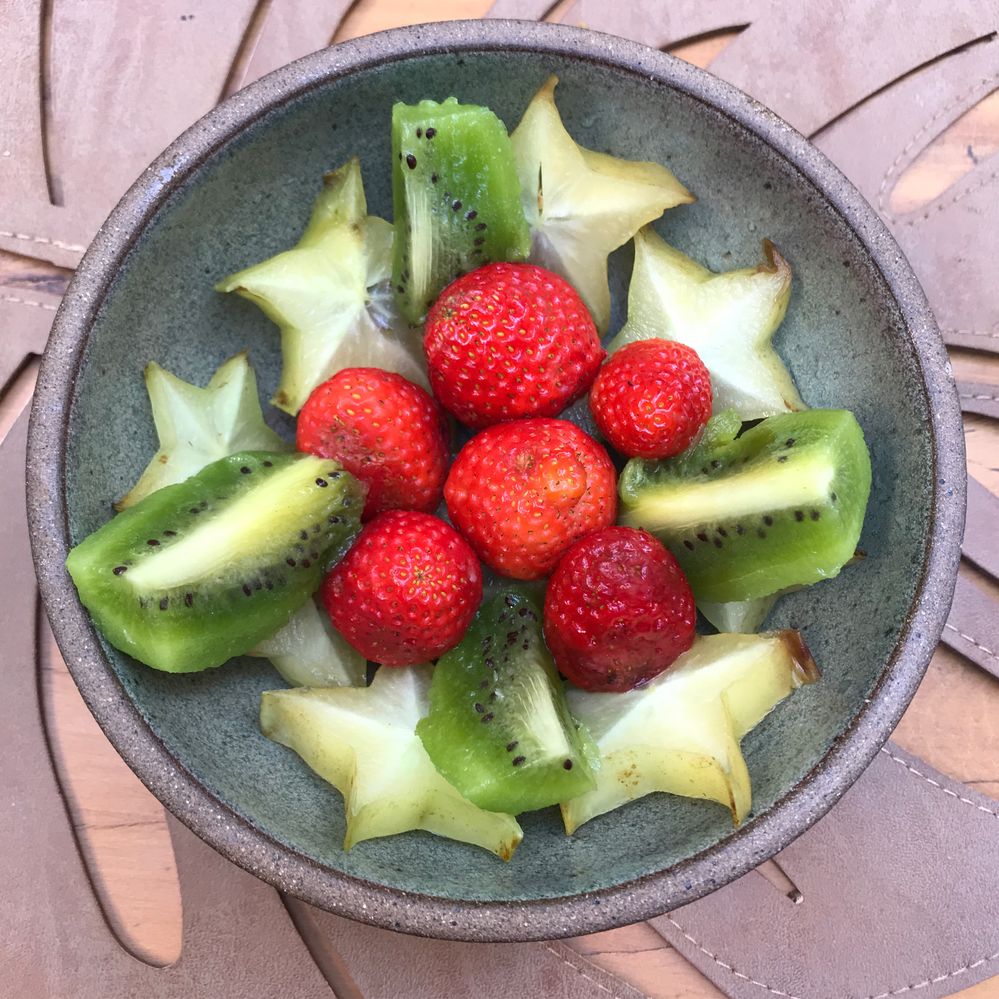 Caption: A photo of a grey bowl filled with strawberries, pieces of kiwis, and another star-shaped fruit from BotaniKafé in São Paulo, Brazil. (Local Guide Nanda Cury)
