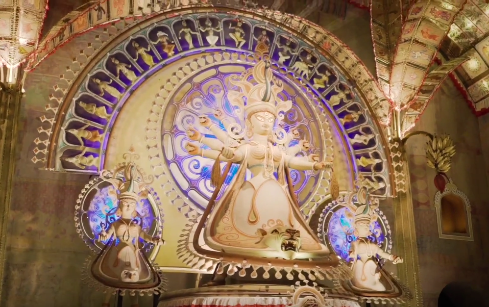 Caption: A screenshot from a Local Guides YouTube video, “Durga Puja in Kolkata - Festivals Around the World, Ep. 1,” showing a golden idol inside a Durga Puja pandal in Kolkata, India.