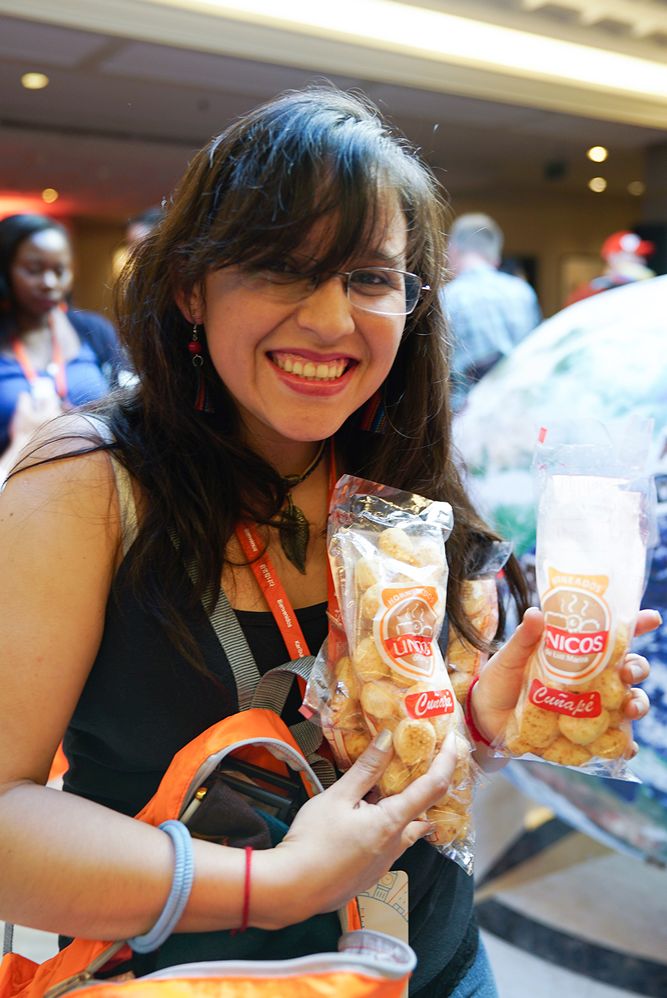 Caption: A photo of Local Guide Gabriela holding up two bags of cuñapé, traditional baked cheese balls from Bolivia, at Connect Live 2018.