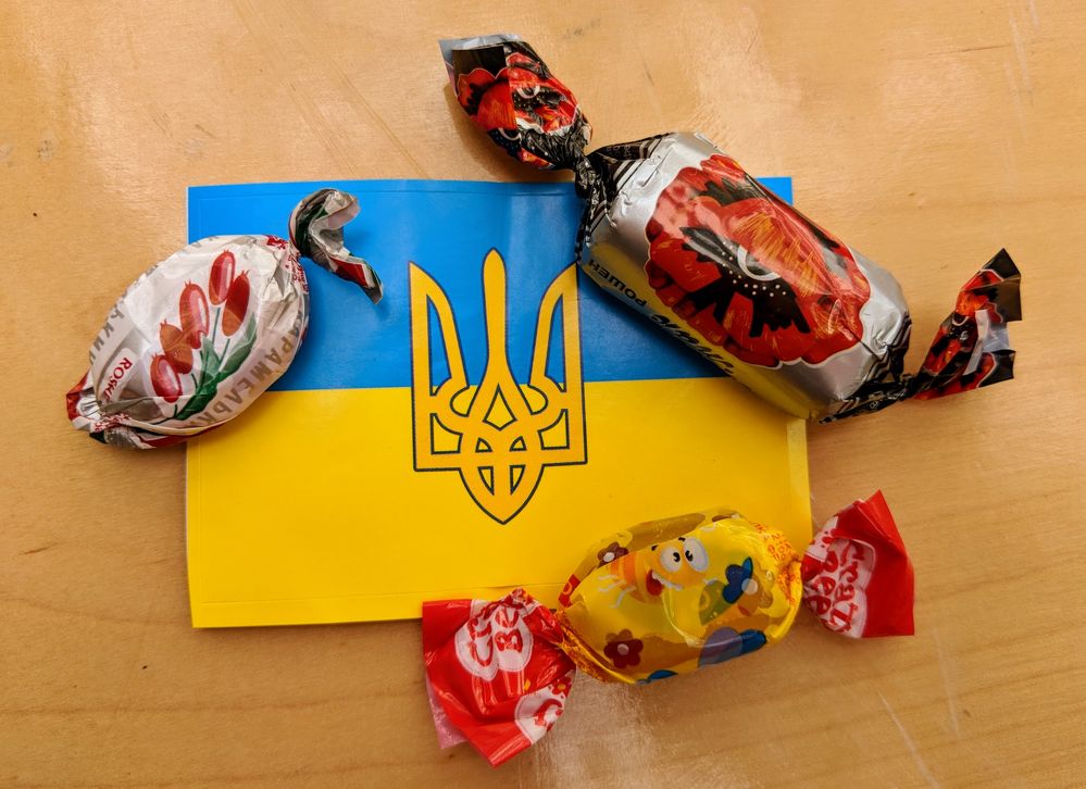 Caption: A photo of three wrapped candies on top of a sticker of the Ukrainian flag and trident.