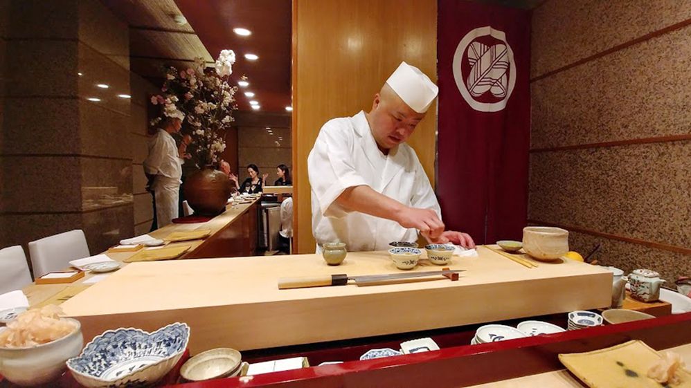 Caption: A photo of a chef making sushi at a counter at Sushi Kanesaka in Tokyo, Japan. (Local Guide Mike Lee)
