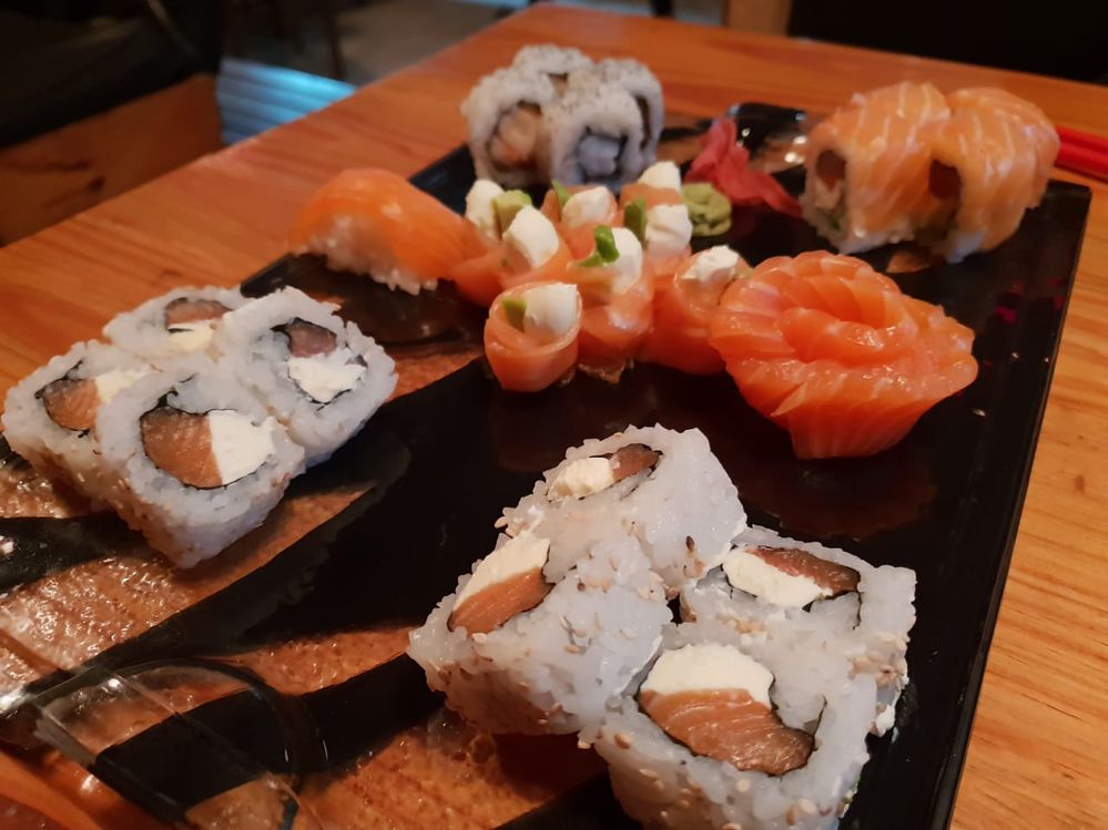 Caption: various sushi pieces gracefully arranged on a glass  plate.