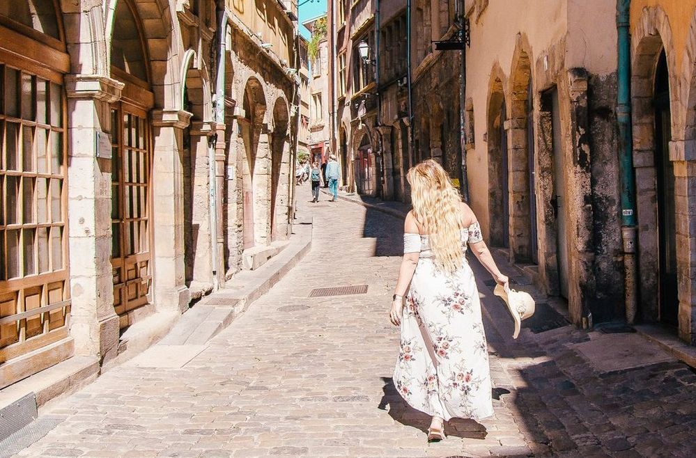 Caption: A photo of Local Guide @Fernwehsarah taken from behind as she walks through a cobblestone street in Lyon, France. (Local Guide @Fernwehsarah)