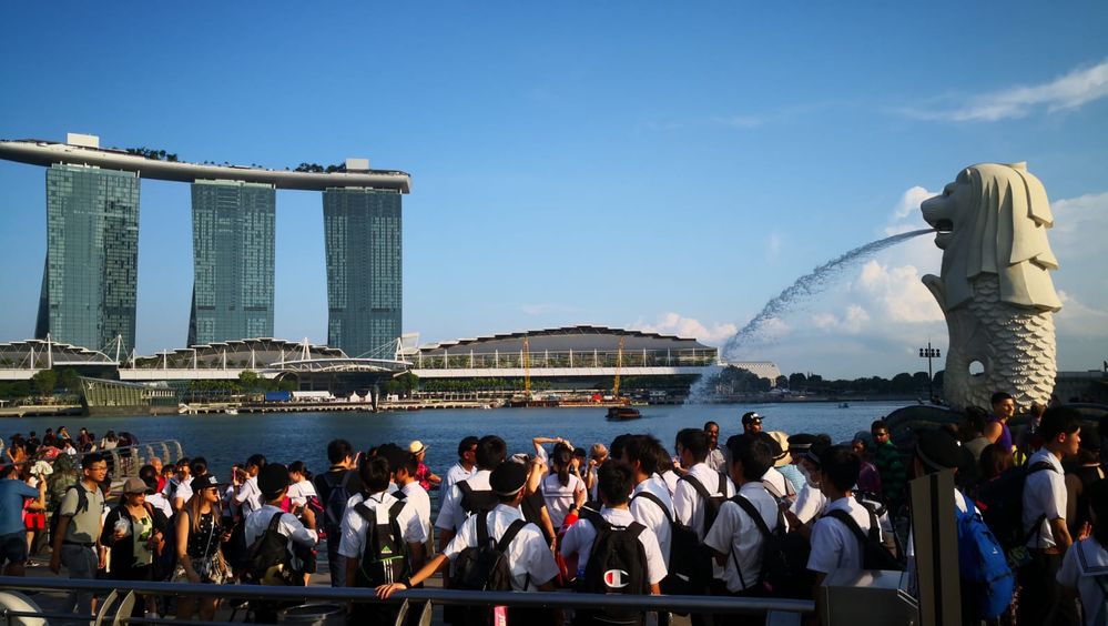 Caption: A photo of people surrounding The Merlion fountain in Merlion Park in Singapore. (Local Guide @DoriyaKiz)