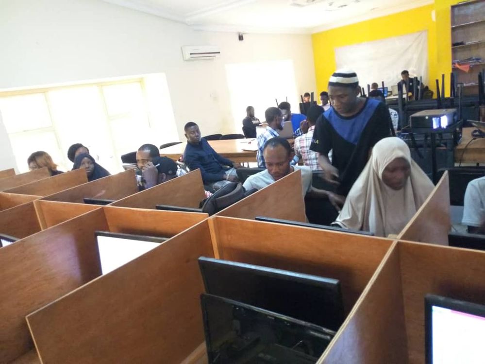 Caption a photo of Abdullahi teaching members of his community how to code