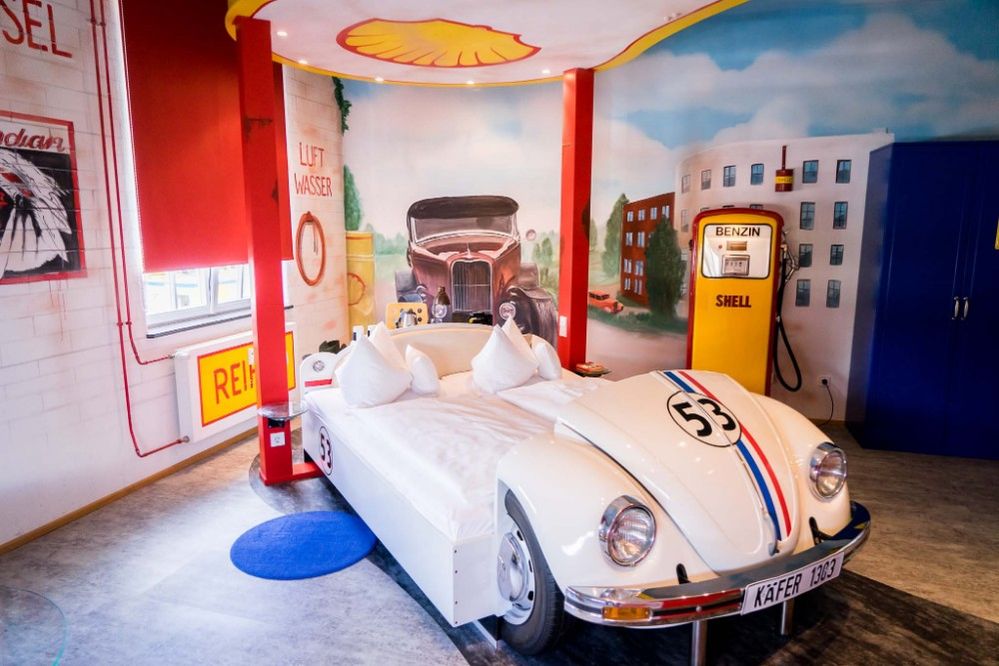 Caption: A photo of a room at the V8 Hotel with a bed designed to look like a car at a gas station. (Local Guide Michael Turtle)