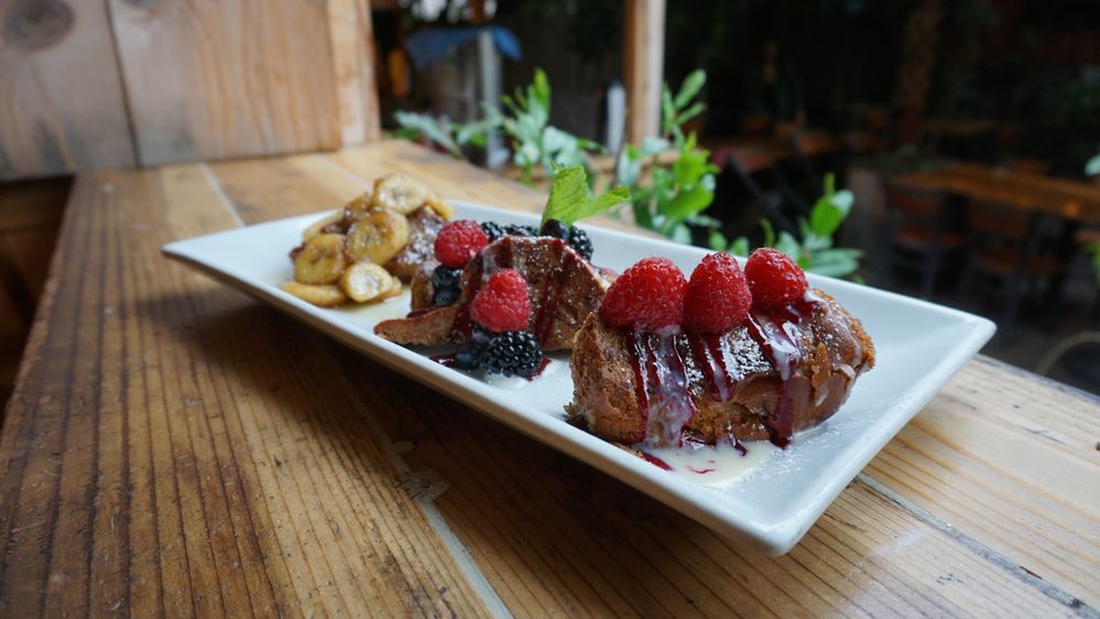 Caption: A photo of a French toast sampler served at Fig Tree Cafe Pacific Beach in San Diego, California, United States. The dish includes one topped with raspberries, another topped with blueberries, blackberries, and raspberries, and the third topped with sliced bananas. (Local Guide Diana Duangnet)